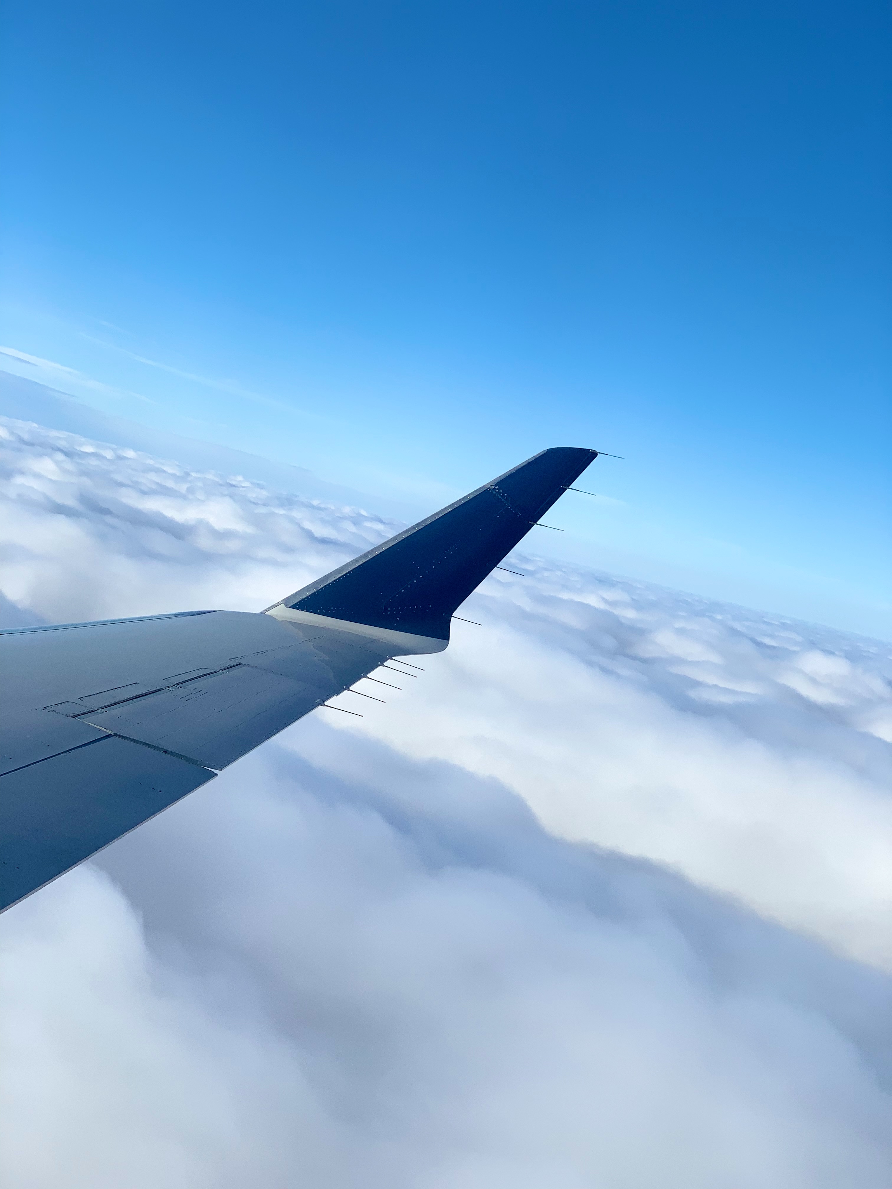 An airplane wing above a sea of white clouds