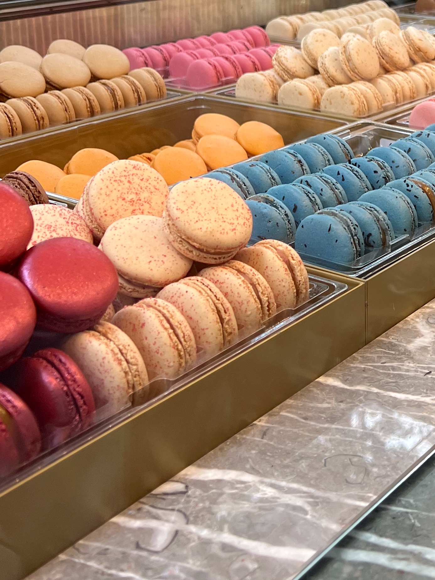 Rows of colorful macarons in a Paris pastry case
